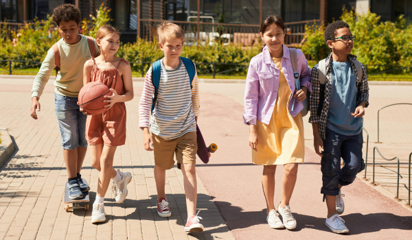 Group of children walking or riding skateboards to school
